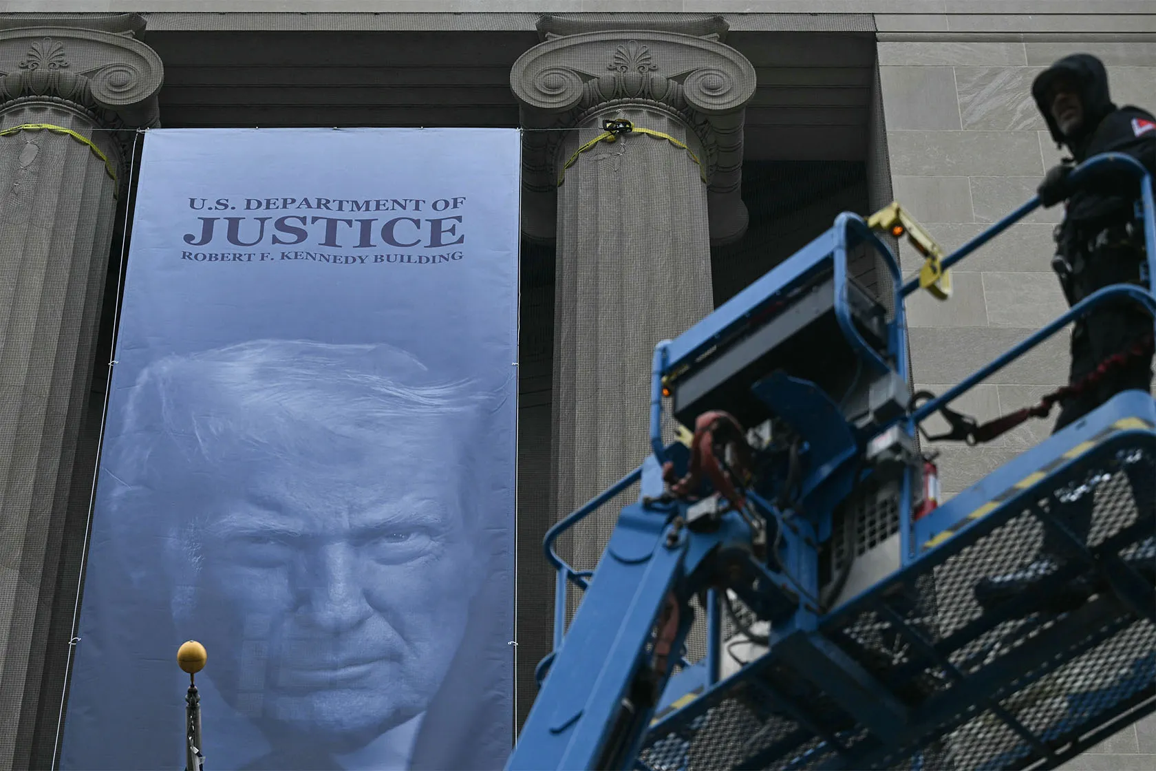 A banner with President Trump's face on it is installed on the Department of Justice building.