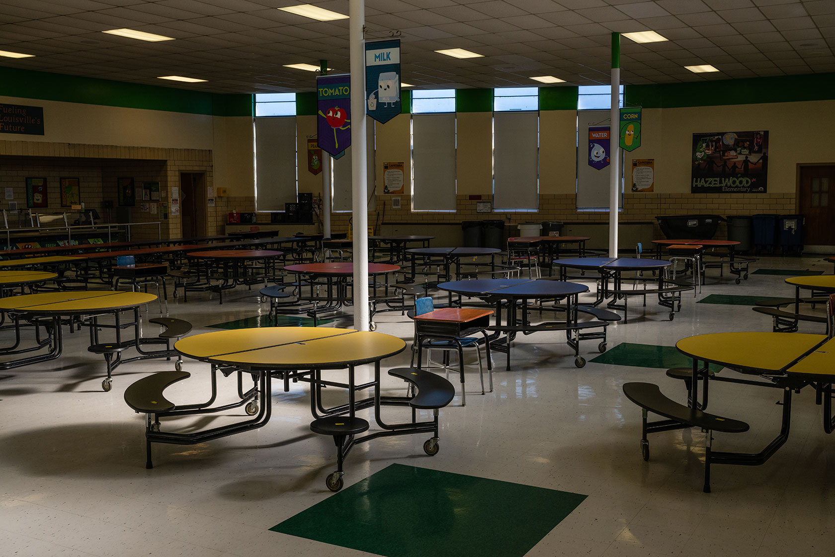 Unused lunch table under low lighting; posters related to food are seen