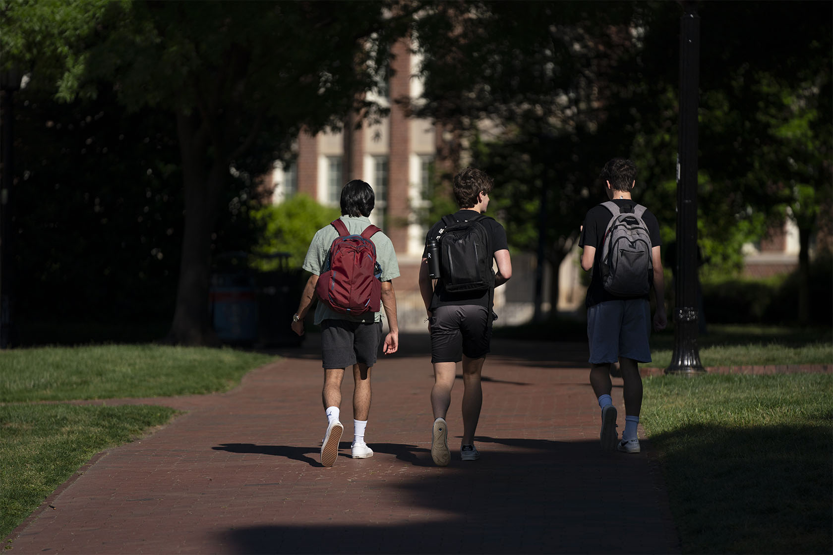 Three students walk on a college campus.