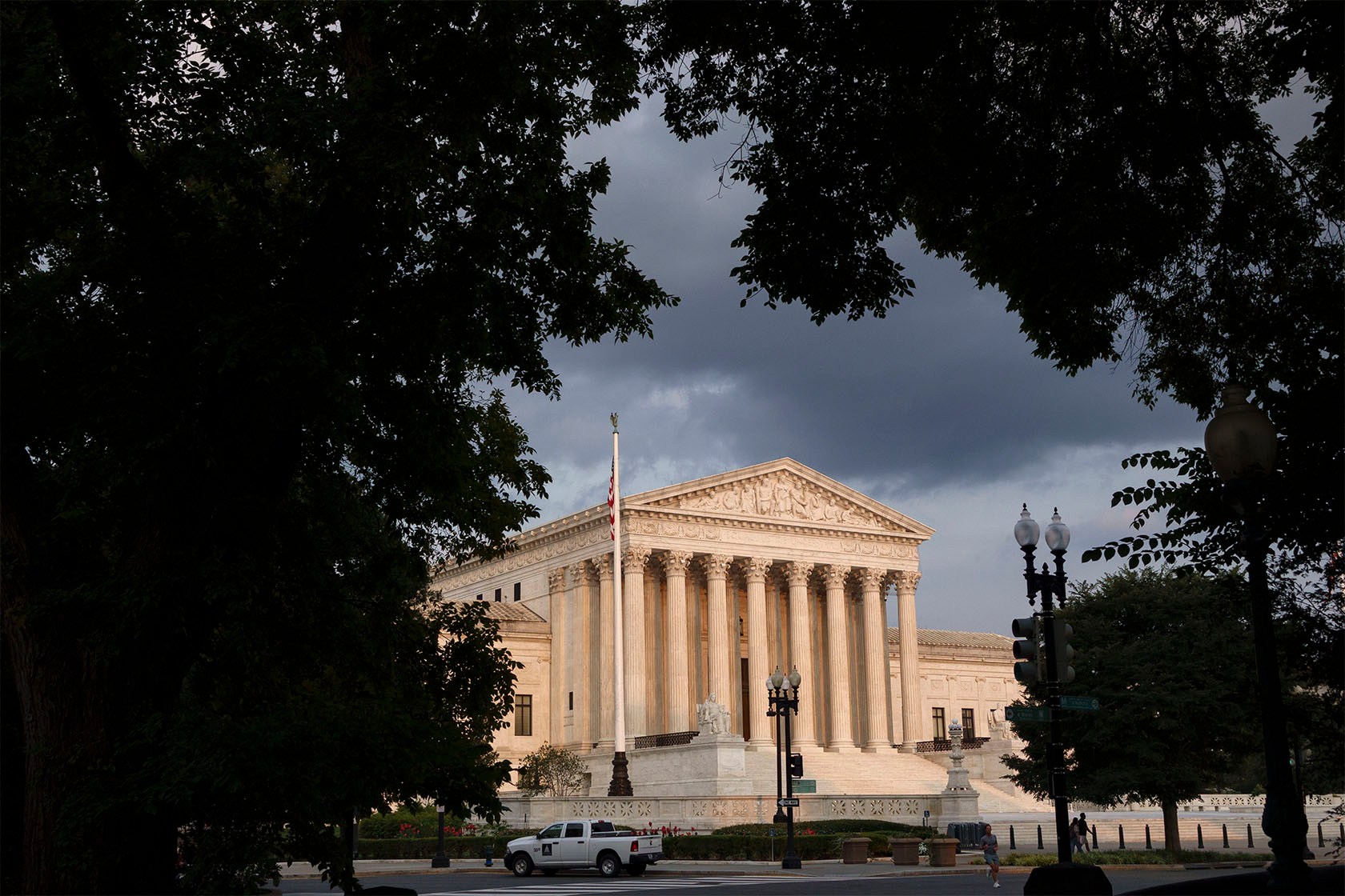The U.S. Supreme Court at sunset seen through trees.