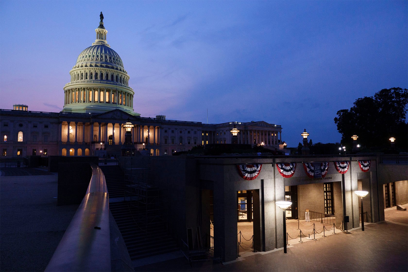 The U.S. Capitol dome lit at dusk, above the visitor center entrance.