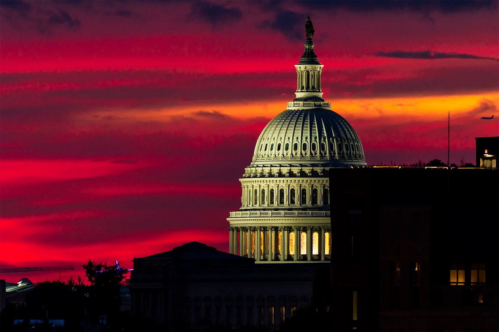 The sun sets behind the U.S. Capitol in Washington, D.C., creating a red and orange sky.