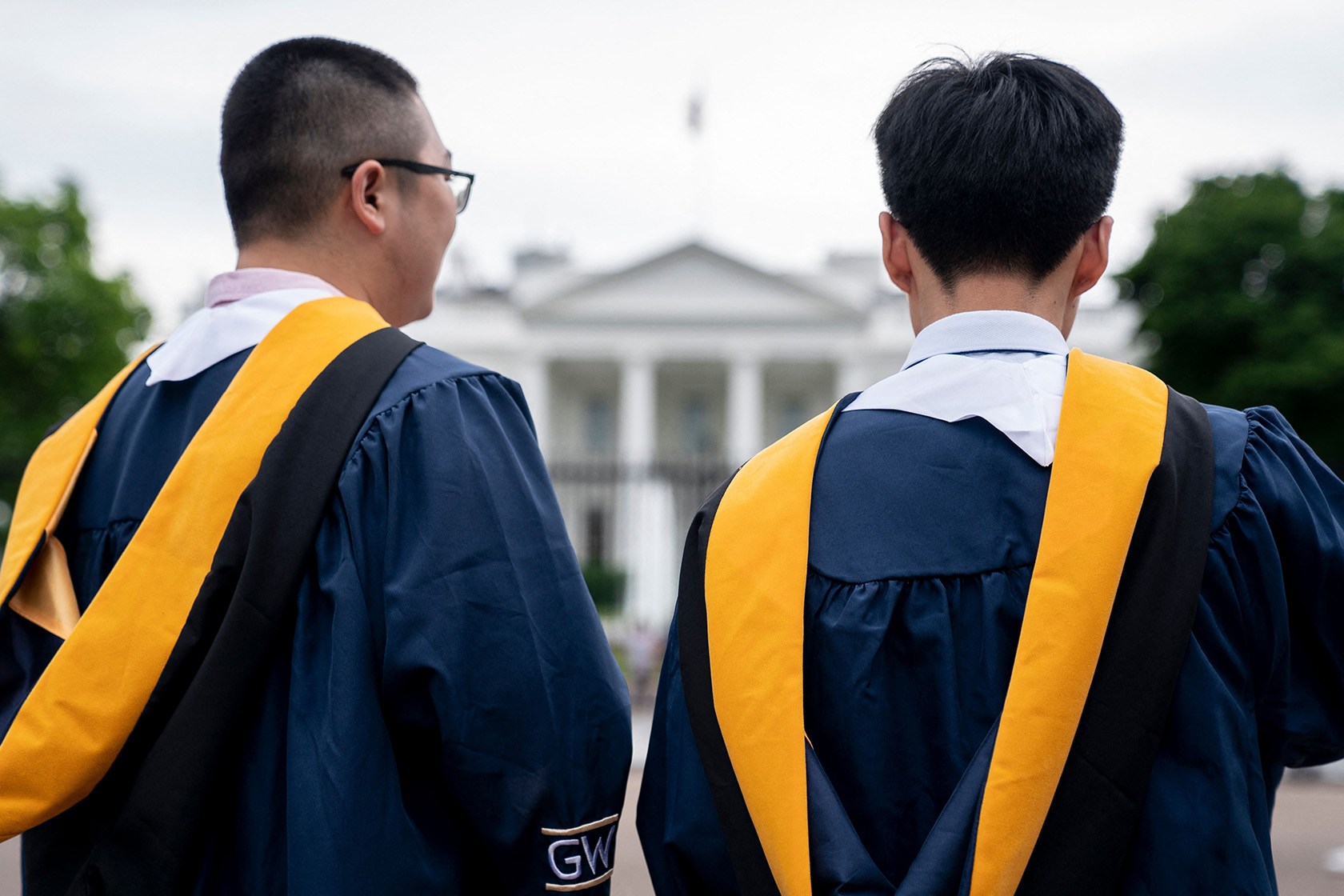 University students wear their graduation gowns outside the White House.